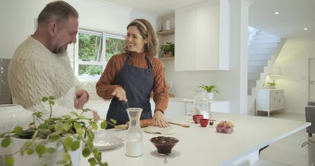 Upon reaching kitchen island couple brushing flour and rolling dough for baking with rolling pin - Powered by Adobe