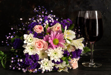 Bouquet of flowers and two glasses with wine close-up