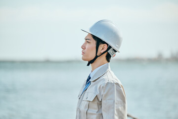 遠くを見つめる作業服姿の男性