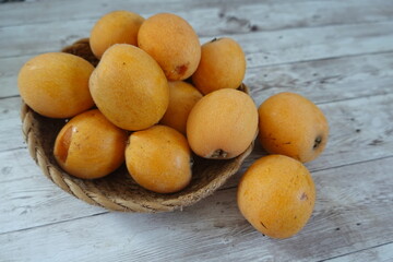 Fresh loquats overflowing a rustic woven basket