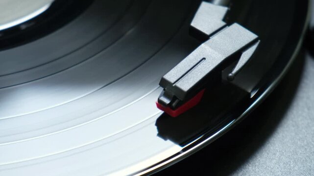 Detailed macro view of a stylus needle tracking the grooves of a spinning vinyl record on a turntable