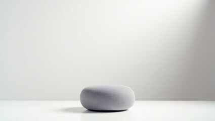 A gray, round ottoman in a minimalist setting.