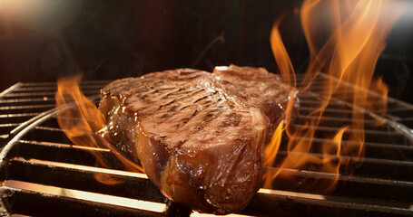 T-bone steak grilling on fire on a barbecue grill