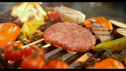 Chef grilling hamburger and vegetables on barbecue for summer party