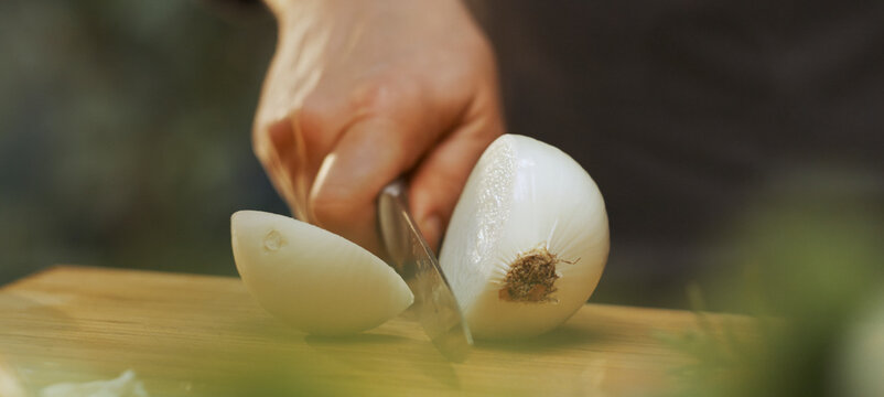 Chef cutting white onion on wooden board - Powered by Adobe