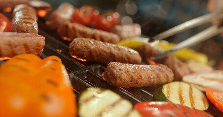 Chef grilling sausages and vegetables on barbecue for summer party