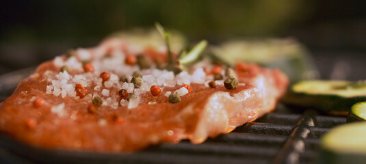 Delicious seasoned steak grilling on barbecue with zucchini slices