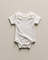 Top-down view of a blank white baby bodysuit with subtle fabric folds on a seamless beige background.