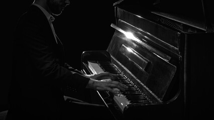 Close up of male pianist playing piano in dark dramatic lighting. Concept of music festival posters, streaming service covers, audio brand campaigns, mindfulness, and piano courses.