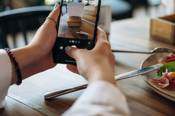 Scanning the QR code by smartphone. Close up view of teenage girl that is sitting in the cafe restaurant