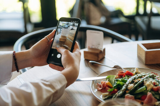 Scanning the QR code by smartphone. Close up view of teenage girl that is sitting in the cafe restaurant