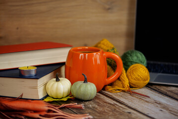 A Cozy Autumn Scene Featuring Books, a Pumpkin, and Colorful Yarn for Perfect Ambiance
