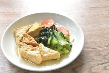 stir fried Chinese cabbage with needles mushroom and carrot topping tofu in soy sauce on plate