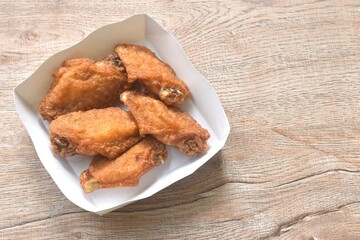 crispy fried salty chicken wing arranging in papay tray packaged on table