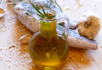 Fresh fish and olive oil in the bottle with herbs and mediterranean spices