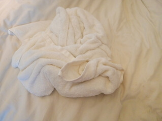 a white towel used on the bed in the hotel room. 