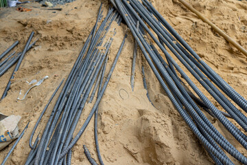 Close-up of steel rebar bundles on a sandy construction site, ideal for building and industrial...