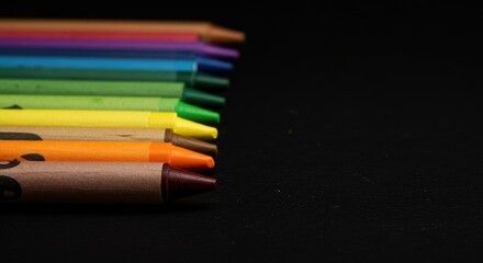 Fototapeta premium Crayons in a rainbow of colors against a black background