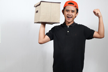 Excited delivery man celebrating successful delivery with box in hand and cap orange, cheerful and...