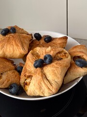 Freshly baked puff pastry with cottage cheese filling and blueberries on white plate. 