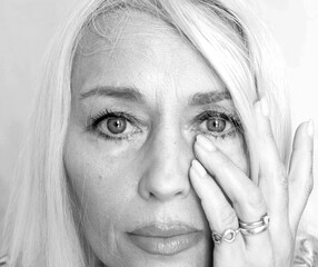 Emotional close-up portrait of a confident woman touching her face — black and white beauty and...