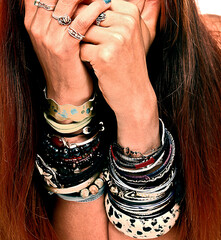 Woman with long red hair, hands covering face, wearing many rings and bracelets