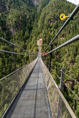 Hängebrücke mit Sicherheitskamera über bewaldeter Schlucht im Sarntal