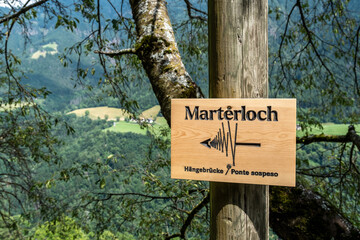 Holzschild mit Wegweiser zur Hängebrücke Marterloch im Sarntal