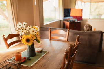 Vase filled with fresh flowers in rustic Australian country kitchen with person on couch watching TV