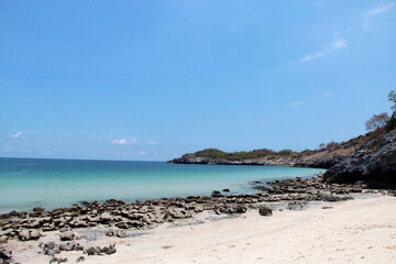 Serene rocky beach cove at Ko Si Chang island, Thailand with clear turquoise water and blue sky