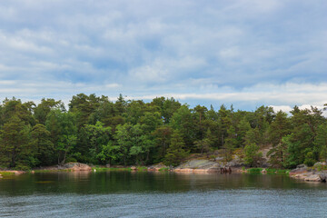 A peaceful coastal scene from a Finnish archipelago with pine trees, sea, and granite rocks. Protecting fragile island ecosystems and preserving the natural heritage. Jussaro, 2025