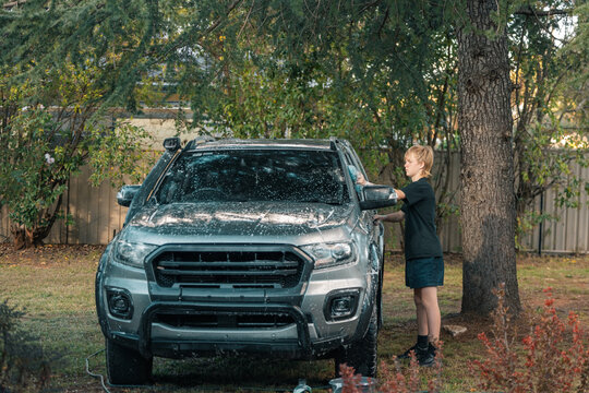Teen boy hand washing car at home with blue sponge