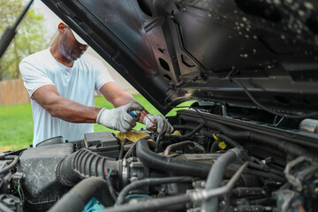 A portrait of a black man installing a car battery
