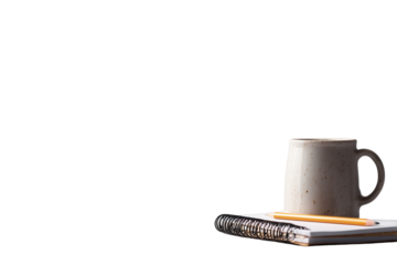 A warm mug of coffee sits on an open notebook with a pencil bathed in soft light against a dark background