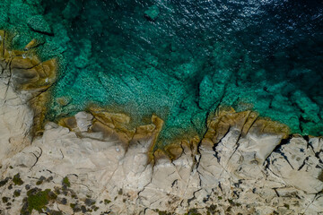 Aerial shot of a coastal landscape with clear blue waters.