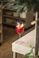 Red cocktail with orange slice and ice in elegant wine glass