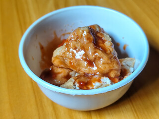 Pentol tofu served in a white bowl, pieces of tofu and meatballs covered in thick red chili sauce. Looks very delicious and delicious.