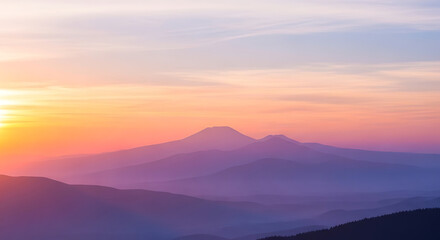 Obraz premium Majestic mountain peaks bathed in the warm glow of a vibrant sunrise, casting soft hues across the serene landscape.