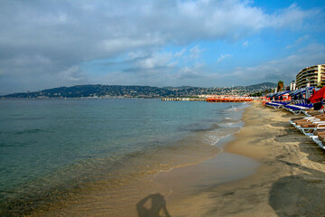 Seaside beach with sun loungers and calm sea in coastal city resort
