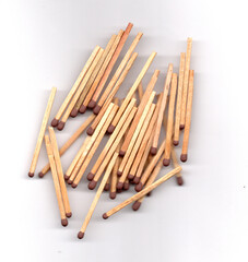 A pile of wooden matches with brown heads scattered on a white background.