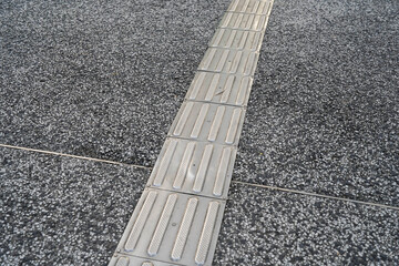 Fototapeta premium Tactile Paving Pathway on Cobblestone Road – Accessible Sidewalk for the Visually Impaired