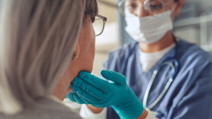The doctor examines an old woman with a sore throat
