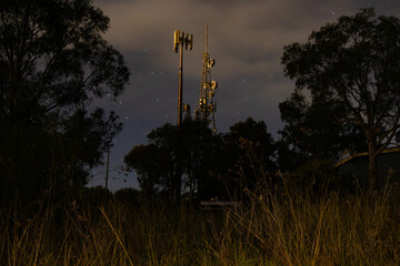 Telecommunications tower illuminated at night with starry background