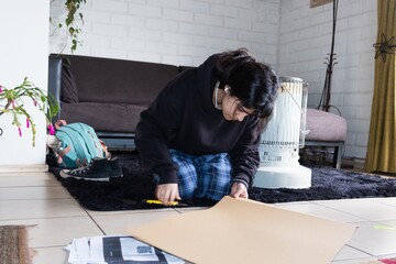 teenager cutting cardboard shapes for school