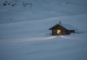 Naklejka premium Cozy cabin glows amidst a vast, snowy landscape, casting a warm light onto the surrounding snow.