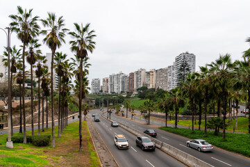 Die Küstenstraße Costa Verde in Lima, Peru, gesäumt von Palmen, mit Hochhäusern in Miraflores im Hintergrund