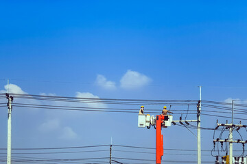 Electricians or engineer on bucket boom truck work to install electrical system on power pole with...