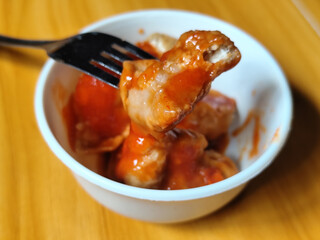 Pentol tofu served in a white bowl, pieces of tofu and meatballs covered in thick red chili sauce. Looks very delicious and delicious.