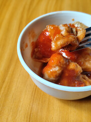 Pentol tofu served in a white bowl, pieces of tofu and meatballs covered in thick red chili sauce. Looks very delicious and delicious.