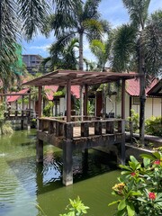 Obraz premium Tropical pond and wooden deck in Thai resort garden